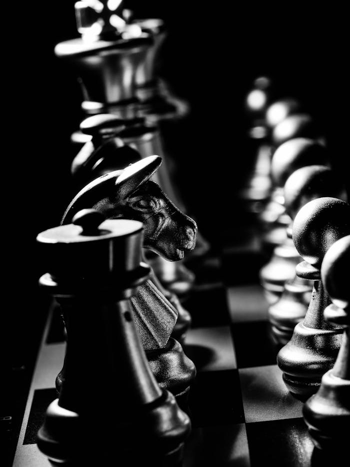 Close-up view of chess pieces in dramatic black and white, capturing strategic intensity.